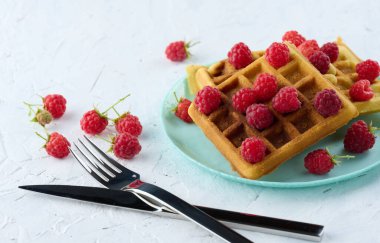 Bir yığın Belçika waffle 'ı ve olgun kırmızı ahududu.