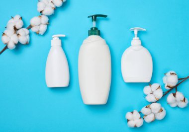 Kozmetik ürünleri için boş beyaz şişeler ve mavi arka planda diğer sıvı maddeler. Marka jeli, şampuan, deterjan. Düz yatıyordu