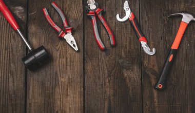 Kahverengi ahşap arka planda bir set inşaat aletleri, üst manzara. Çekiç, pense, ayarlanabilir anahtar.