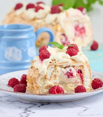 Baked meringue roll with cream and fresh red raspberry, white background	