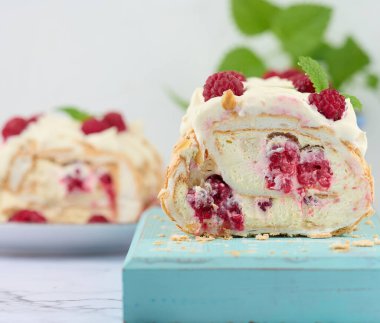 Baked meringue roll with cream and fresh red raspberry, white background	
