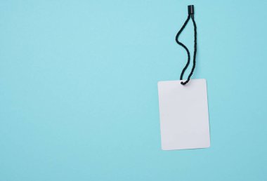 Beyaz ipte boş beyaz karton etiket, mavi arka plan. Fiyat etiketi şablonu