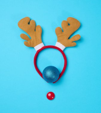 Mavi arka planda boynuzları olan Noel geyiği kostümü..