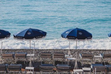 Güzel, Fransa - 29.09.2022: Akdeniz kıyısında Blue Beach Nice 'in açık şemsiyeleri ve güverte sandalyeleri