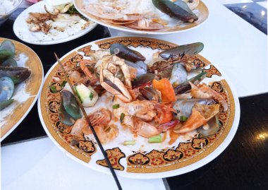 Doymak bilmeden deniz ürünleri yiyen ve sadece midye ve kirli deniz ürünleri tabakları bırakan bir turist.