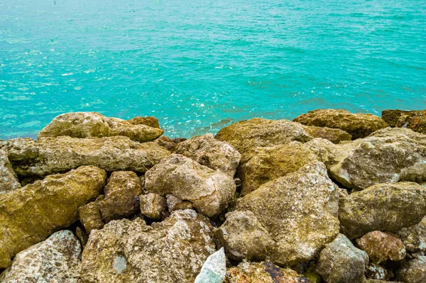 Mavi dalgalı okyanusla çevrili sarı ve gri büyük taşlar, berrak mavi deniz suyunun yanında büyük kayalar, kayalı mavi deniz suyunun güzel panoramik manzarası