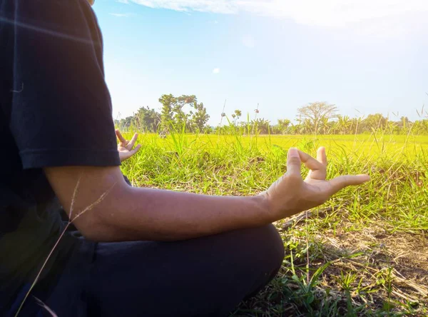 young asian man doing yoga practice in nature, sitting in lotus pose and meditating in open nature in peaceful and beautiful nature atmosphere. lifestyle concept