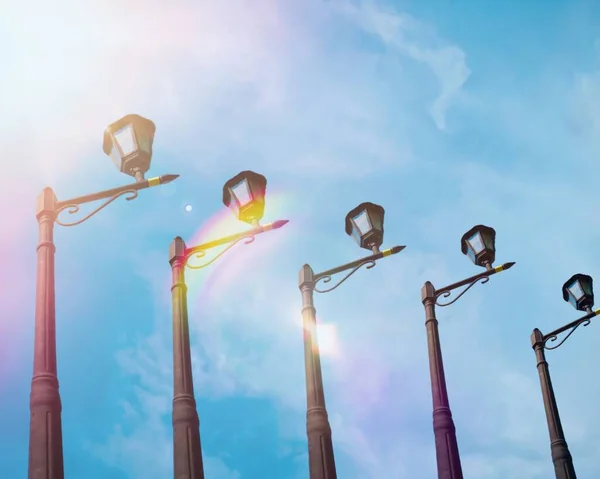 Garden light poles lined up in the garden against the background of white clouds in a bright blue sky and the light of the sun shining in the morning