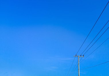 electric pole in a minimalist composition on a bright blue sky with empty space to enter text