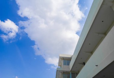The side of the office building in the outer corner with a bright blue sky. Exterior office building wall and morning blue sky