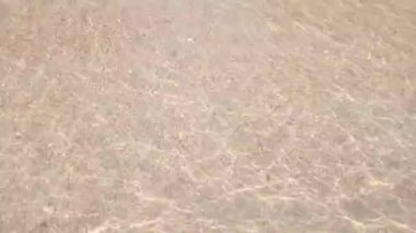 Küçük deniz suyu dalgaları kumsalda ileri geri hareket ediyor. Deniz dalgaları yaz tatilinde kumsalda yumuşak köpükle yavaşça hareket eder. 