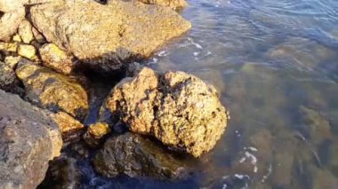 Öğleden sonra büyük kayalara vuran denizin dalgaları