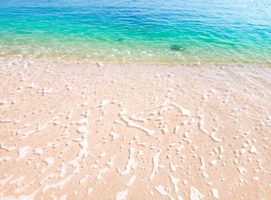 Temiz ve köpüklü mavi deniz suyu dalgaları ve temiz kumlu kumsalla güzel bir sahil.. 