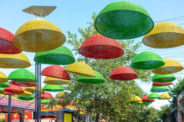 There are umbrellas hanging over the park alley. Against the background of the blue sky, umbrellas with colorful autumn colors. Colorful picture.