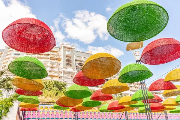 There are umbrellas hanging over the park alley. Against the background of the blue sky, umbrellas with colorful autumn colors. Colorful picture.