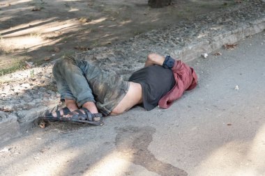 Homeless and sick man lying helplessly on the street