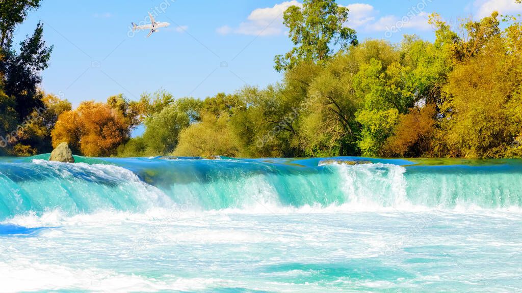A white passenger plane flies over a waterfall on the Manavgat River, Antalya. Turkey