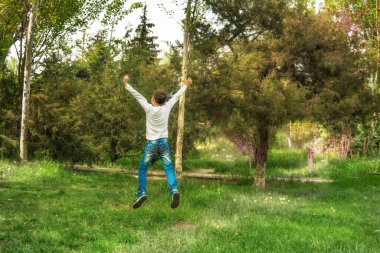 Ormanda havaya atlayan mutlu çocuk.