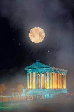 Pagan tapınağı Garni 'nin gece görüşü ayın arka planında, sis ve duman içinde, Ermenistan Cumhuriyeti' ndeki Helenistik tapınak.