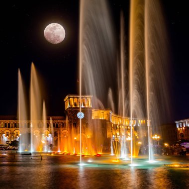 Erivan 'daki Cumhuriyet Meydanı' nda şarkı söyleyip dans eden fıskiyeler. Gece şehir ışıkları dolunaya karşı.