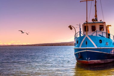 Gün batımında Sevan Gölü 'ndeki iskeleye park edilmiş küçük bir zevk gemisi.