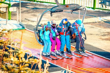 Dört kayakçıdan oluşan bir grup kayak yoluna tırmanmak için teleferiği kullanıyor.