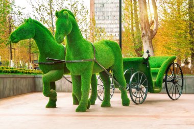 Üç boyutlu yeşil at ve at arabası heykeli. 