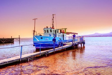 Küçük bir zevk gemisi güzel bir gün batımının arka planına karşı kıyıdaki rıhtımda park halinde.