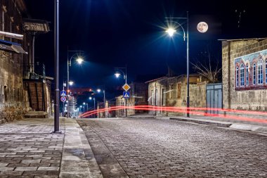 Eski kasabanın gece manzarası. Uzun pozlar ve arabanın farlarından gelen izler.