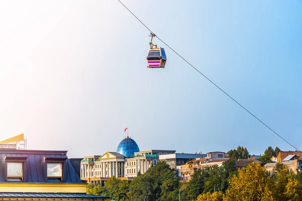 The cable car moves over the center of Tbilisi . Building of the Presidential Palace of Georgia on background