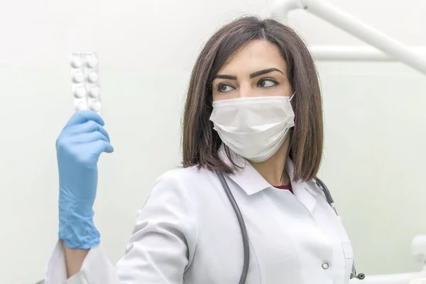 身穿白色医疗服和蓝色手套的年轻女医生用水泡包装为药品做广告 — 图库照片