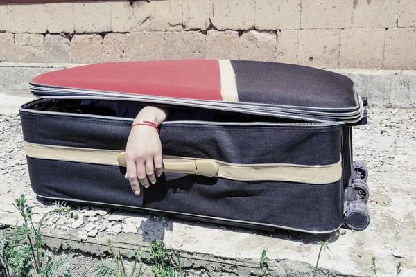 Female hand coming out of a suitcase. Imitation of the murder of a woman by a maniac or serial killer.