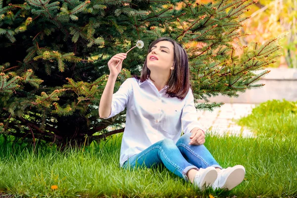 Parkta beyaz karahindiba üfleyen bir kız