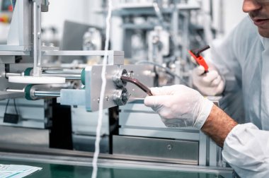 Koruyucu giysi giyen bilim adamları, endüstriyel bir fabrikanın laboratuarında maske yapan bilim adamları. Anti-virüs üretim deposu. Güvenlik ve önleme konsepti Coronavirus covid-19.