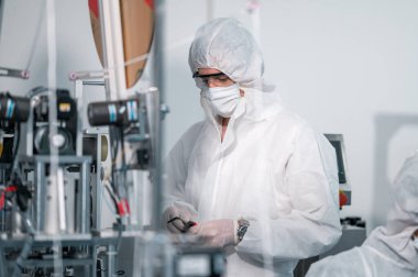 Koruyucu giysi giyen bilim adamları, endüstriyel bir fabrikanın laboratuarında maske yapan bilim adamları. Anti-virüs üretim deposu. Güvenlik ve önleme konsepti Coronavirus covid-19.