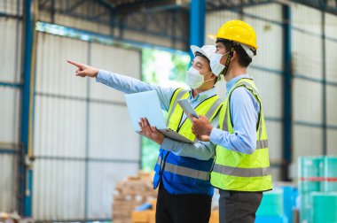 Mühendisler ve ustabaşı maske, şapka ve yelek giyerler. Endüstriyel üretim yönetimi hakkında görüşeceğim. İş detaylarını fabrikalarda veya depolarda dizüstü bilgisayarlar ve tabletler yoluyla açıklamak.