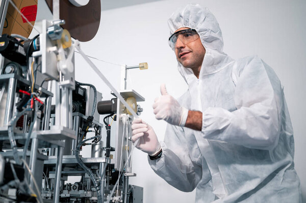 Scientists wearing protective clothing Inspect mask making machines in a laboratory at an industrial plant. Anti-virus production warehouse. concept of safety and prevention coronavirus covid-19.