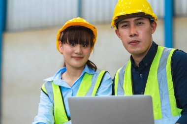 Mühendisler ve ustabaşı maske, şapka ve yelek giyerler. Endüstriyel üretim yönetimi hakkında görüşeceğim. İş detaylarını fabrikalarda veya depolarda dizüstü bilgisayarlar ve tabletler yoluyla açıklamak.