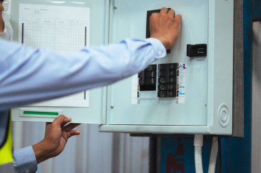 Mühendis, Denetmen ya da Foreman erkeği maske, şapka ve yelek giyer. Fabrikadaki güç kontrol panelini ve elektrik sistemini kontrol ediyorum. iş güvenliği için.