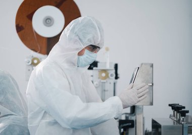 Koruyucu giysi giyen bilim adamları, endüstriyel bir fabrikanın laboratuarında maske yapan bilim adamları. Anti-virüs üretim deposu. Güvenlik ve önleme konsepti Coronavirus covid-19.