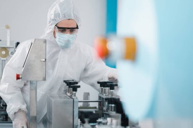 Koruyucu giysi giyen bilim adamları, endüstriyel bir fabrikanın laboratuarında maske yapan bilim adamları. Anti-virüs üretim deposu. Güvenlik ve önleme konsepti Coronavirus covid-19.
