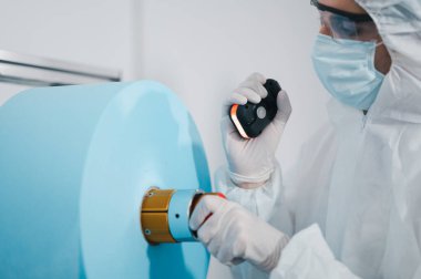 Bilim adamları üniforma giyiyorlar. Yüz maskelerinin üretim sürecini kontrol et. Sanayi tesislerindeki bir laboratuvarda. Güvenlik ve koruma konsepti Coronavirus covid-19.