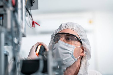 Koruyucu giysi giyen bilim adamları, endüstriyel bir fabrikanın laboratuarında maske yapan bilim adamları. Anti-virüs üretim deposu. Güvenlik ve önleme konsepti Coronavirus covid-19.