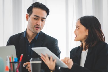 İş kadını, toplantı odasında gülen yüzlü bir arkadaşla tablet ekranda çizelgeleri ve grafikleri tartışıyor. Beyin fırtınası ve takım çalışması konsepti.