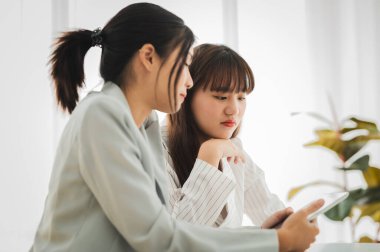 İş kadını, toplantı odasında gülen yüzlü bir arkadaşla tablet ekranda çizelgeleri ve grafikleri tartışıyor. Beyin fırtınası ve takım çalışması konsepti.