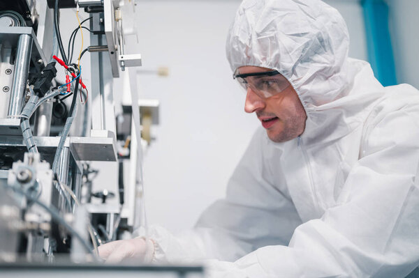 Scientists wearing protective clothing Inspect mask making machines in a laboratory at an industrial plant. Anti-virus production warehouse. concept of safety and prevention coronavirus covid-19.