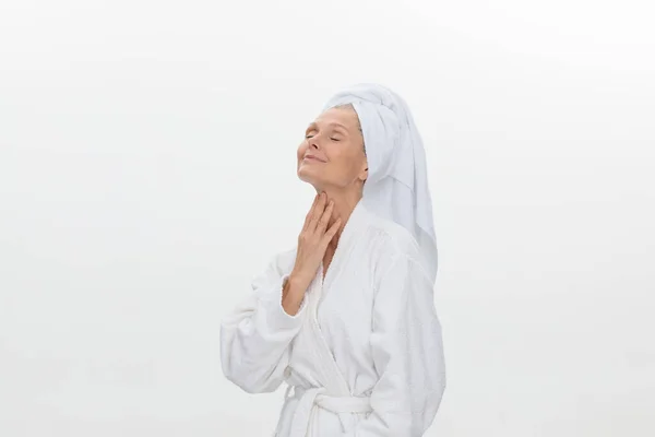 Uma bela mulher madura vestindo um roupão de banho branco e uma toalha enrolada em torno de sua cabeça. — Fotografia de Stock