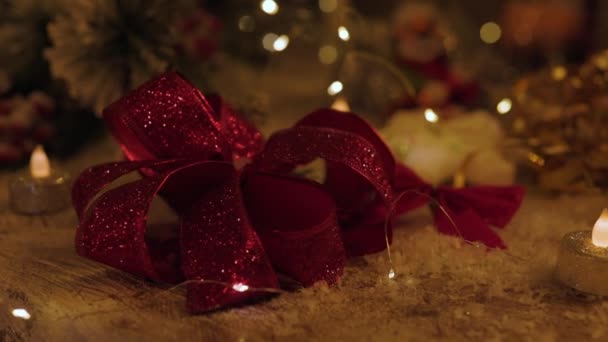 Christmas decoration with three red candles, spruce branches, cones, balls and garland on white table on blurry background. Side view. Hand of woman removes one candle. New year mood — Stockvideo