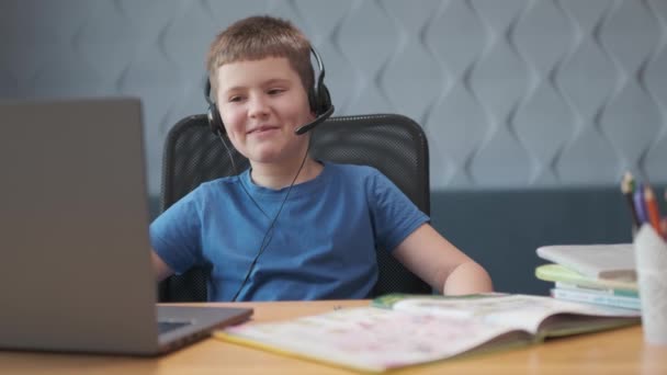 Glimlachende student jongen studeren op de computer op afstand school op het web, concept van surfen en zoeken op het internet of andere activiteiten zoals sociale media of online games — Stockvideo