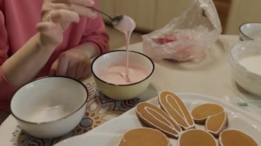 Bir kadın zencefilli kurabiye süslemek için renkli şeker kreması yapıyor..